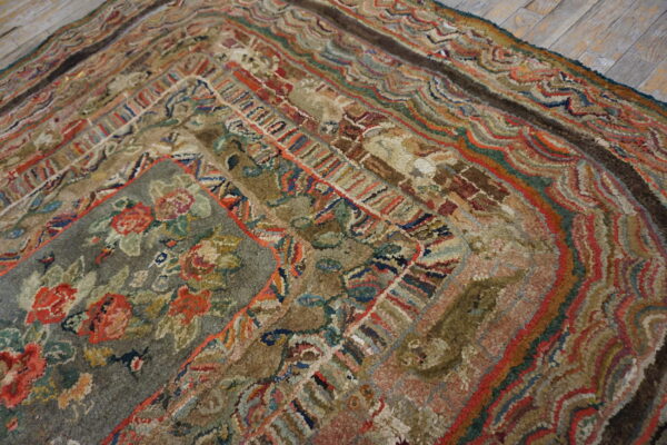 Textured rug with a sage green floral center and multicolored wavy concentric borders on wood flooring.