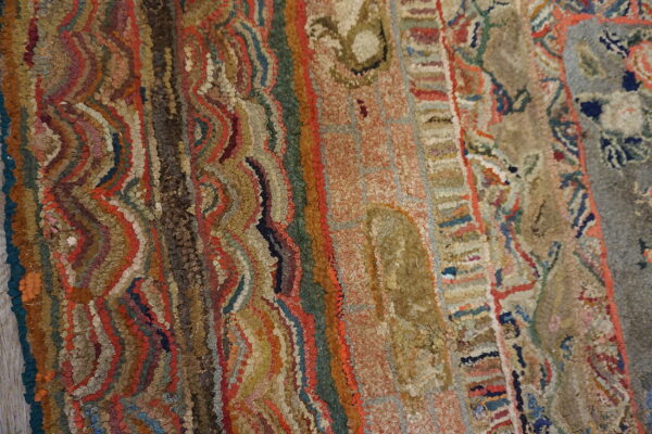 Close-up texture shot of a rugged, multicolored rug with wavy vertical stripes in rust, olive, and beige tones.