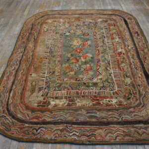 Highly textured oblong rug featuring a gray floral medallion and multicolored borders on a distressed wood floor.