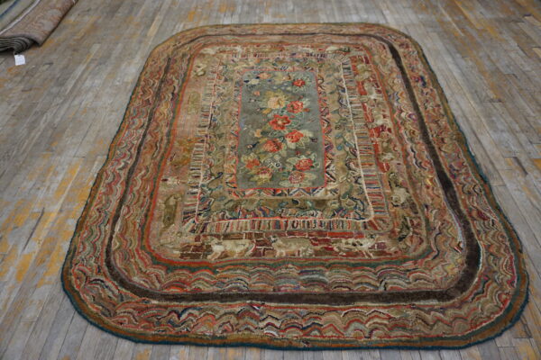 Highly textured oblong rug featuring a gray floral medallion and multicolored borders on a distressed wood floor.