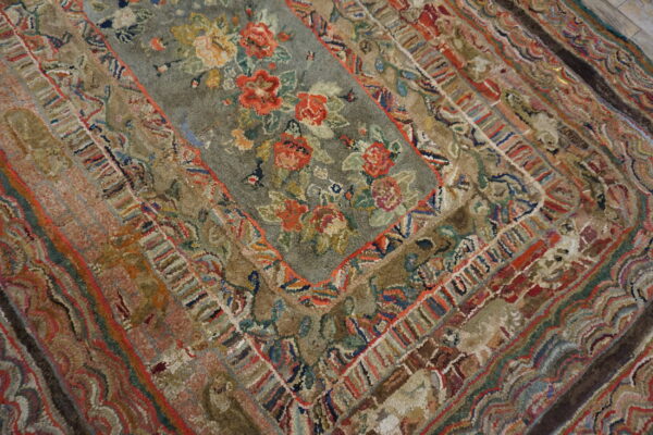Highly textured, multicolored rug featuring a central floral field surrounded by complex, detailed borders.