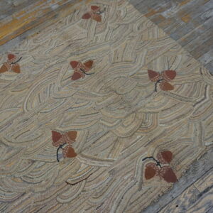 Textured beige rug with wavy lines and scattered brown acorn motifs rests on distressed gray wood planks.