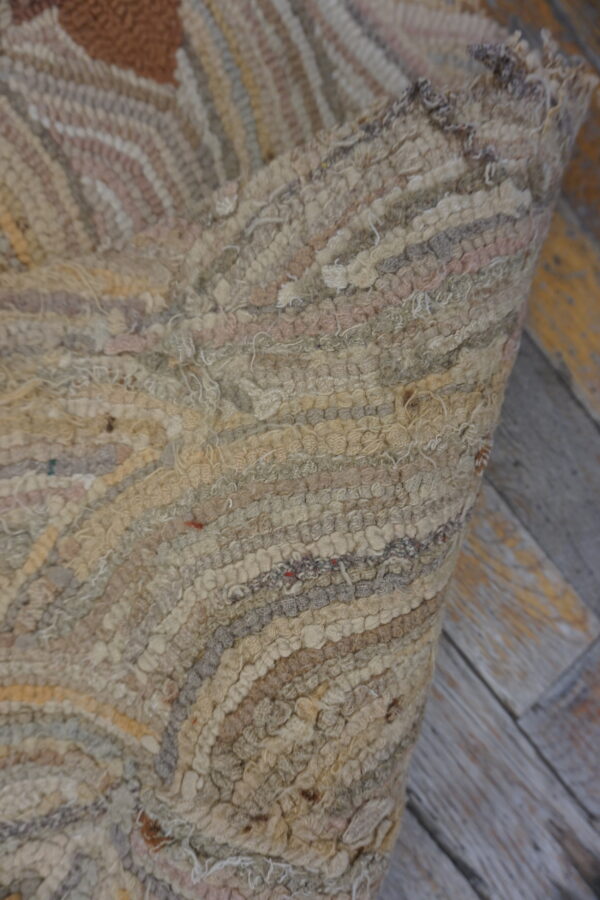 Close-up of a high-pile rug with wavy stripes in neutral beige, gray, and brown tones, lying on distressed wood floor.