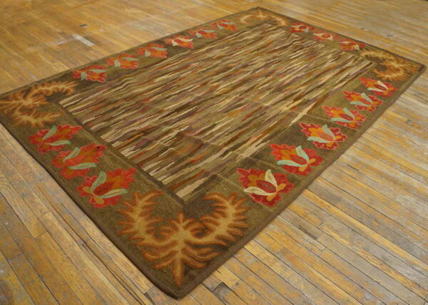 Earth-toned rug with a diagonally striped field and a border featuring large red-orange and gold floral motifs.
