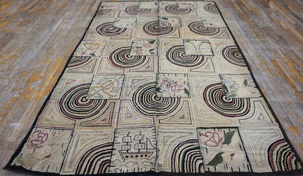 Muted beige textured rug with a black border, showing squares filled with geometric, circular, and folk art designs.