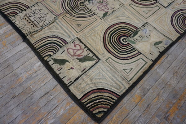 Low-pile rug with geometric blocks and floral patterns in cream, black, green, and purple on worn wood floors.
