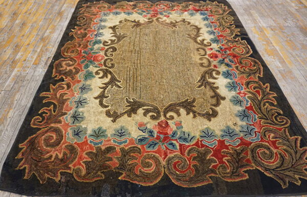 Dark brown, red, and blue ornate rug with sculpted pile lying on light distressed wood flooring.