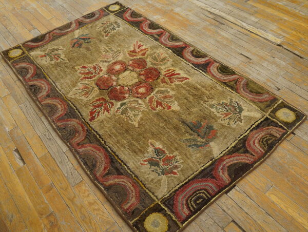 Shaggy tan rug with a rust floral medallion and dark scalloped border on worn wood planks.