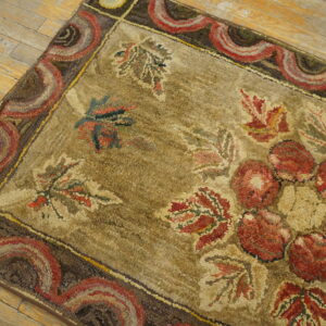 Chunky textured rug displaying large red florals and leaves on a khaki ground with a scalloped border.