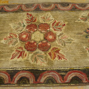 High-texture hooked rug with a red floral center and scalloped border on light wood flooring.