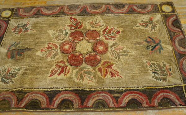 High-texture hooked rug with a red floral center and scalloped border on light wood flooring.