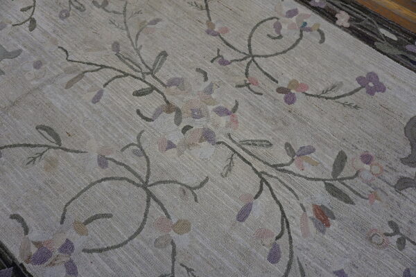 Textured beige rug with scrolling floral pattern in pastel pink, purple, and gray colors.