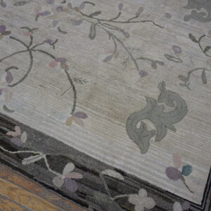Textured cream rug with pale pink and lavender floral pattern and dark multi-toned border on wood.