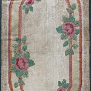 Beige textured rug with an oval pink and orange stripe medallion and climbing pink and green floral designs.