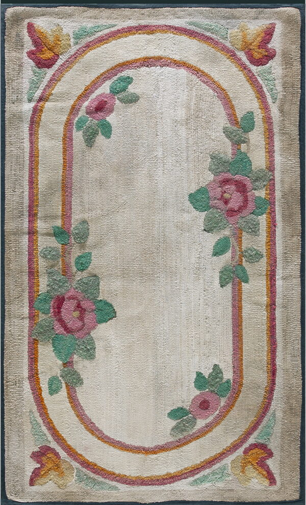 Beige textured rug with an oval pink and orange stripe medallion and climbing pink and green floral designs.