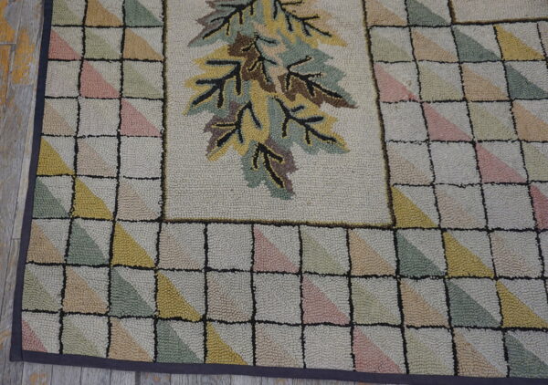 Textured rug with a central leaf design and geometric border of pale pink, green, and yellow triangles.