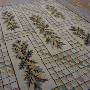 Textured beige rug with brown leaves and multicolored geometric squares rests on rustic wooden floorboards.
