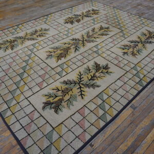 Muted multi-colored hooked rug featuring stylized brown and olive leaf panels on distressed wooden floorboards.
