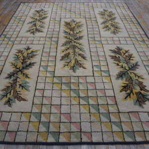Low-pile rug with repeated foliage designs and pastel triangular grid patterns on wooden flooring.