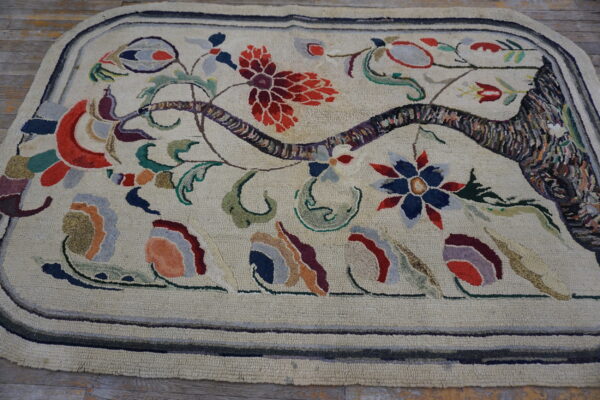 Rounded hooked rug featuring a multicolor botanical pattern on a cream field, visible on wood plank flooring.