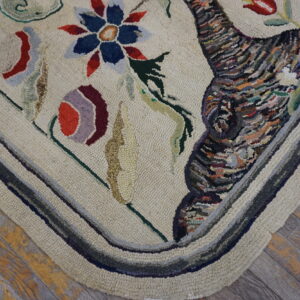 Textured beige rug corner displays colorful floral and abstract patterns with a striped border on distressed wood.