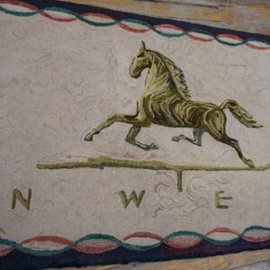 Beige rug featuring an olive green horse and compass design, bordered in red and teal, set on wood planks.