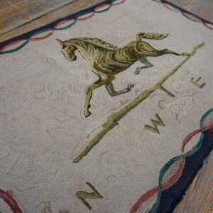 Textured cream rug with a green horse and cardinal directions rests on rustic wooden floorboards.