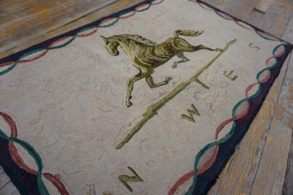 Textured cream rug with a green horse and cardinal directions rests on rustic wooden floorboards.