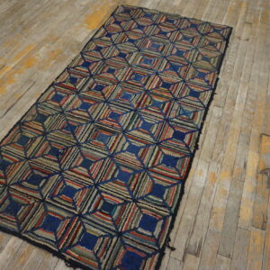 A multicolored rag runner with geometric square pattern sits on distressed wood planks.