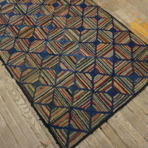 Textured runner rug featuring a multicolored striped diamond pattern and dark blue accents on distressed wood.