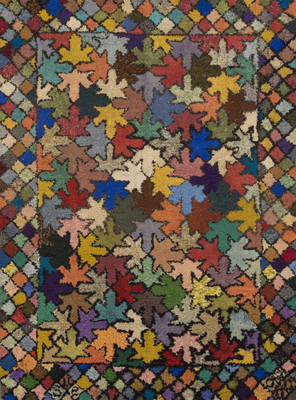 Textured rug displaying multicolored, high-pile leaf shapes surrounded by a variegated diamond border.