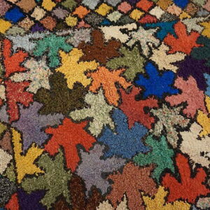 Textured, high-pile rug with variegated colors arranged in large leaf shapes and small diamond patches.