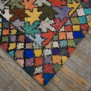 Multicolored high-pile patchwork rug featuring star and square motifs on rustic grey wood planks.