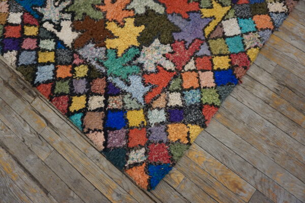 Multicolored high-pile patchwork rug featuring star and square motifs on rustic grey wood planks.