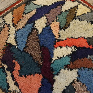 Close-up of a high-texture rug featuring colorful, abstract shag patches against rustic wood planks.