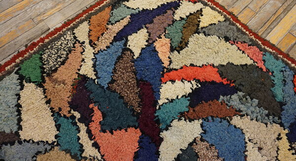 Close-up of a high-texture rug featuring colorful, abstract shag patches against rustic wood planks.