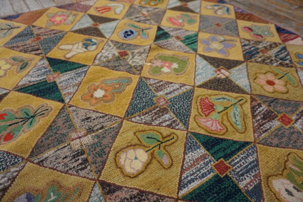 Patchwork rug featuring gold squares with colorful floral motifs interspersed with variegated triangular blocks.