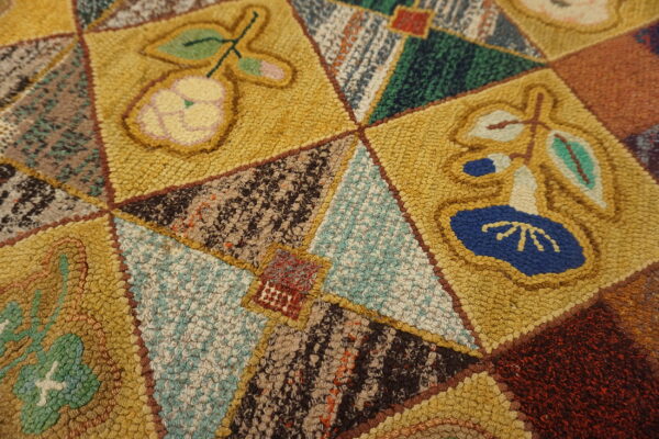 Textured folk art rug closeup with mustard yellow squares, fruit motifs, and multicolored geometric sections.