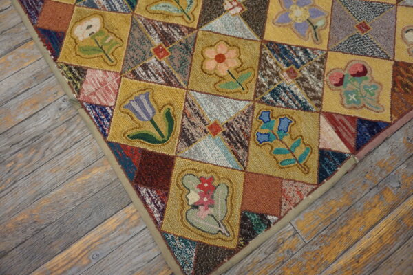 Textured patchwork rug with gold floral squares and multi-colored patches rests on distressed gray wood planks.