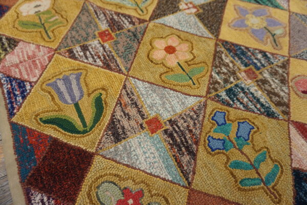 Highly textured, multicolored rug detail featuring golden floral squares and earthy geometric sections.