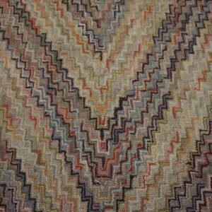 Textured rug with a multicolored stepped zigzag design over a muted gray and beige field.