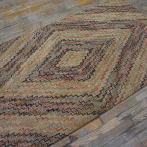 Textured runner rug with a multi-colored chevron diamond pattern on distressed gray wood flooring.