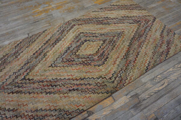 Textured runner rug with a multi-colored chevron diamond pattern on distressed gray wood flooring.