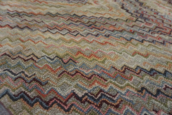 Highly textured rug with multicolored knobby pile forming horizontal chevron patterns in gray, red, and blue.