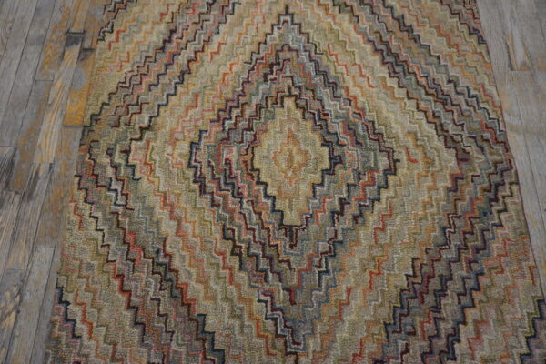 Multicolored, textured rug with a zig-zag diamond pattern resting on weathered gray wood planks.