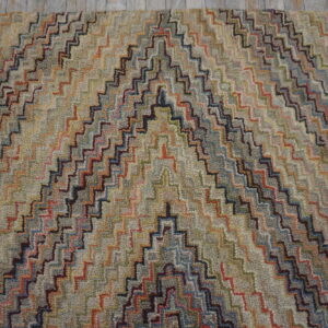 Multicolored chevron rug with a thick, nubbly texture rests on light gray wood flooring.