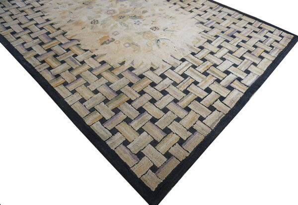 Pale rug featuring a subtle floral center surrounded by a textured border of interwoven light and dark strips.