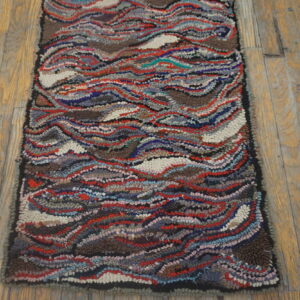Highly textured rug with wavy multicolored stripes of red, blue, and brown on rustic wood planks.