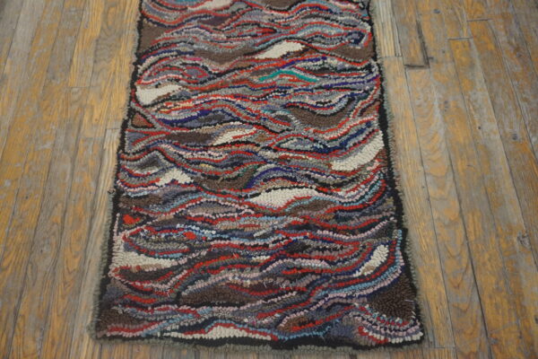 Highly textured rug with wavy multicolored stripes of red, blue, and brown on rustic wood planks.