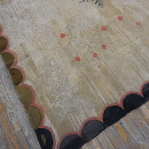 Textured beige rug with faint patterns, pink accents, and a scalloped border resting on rustic wood flooring.